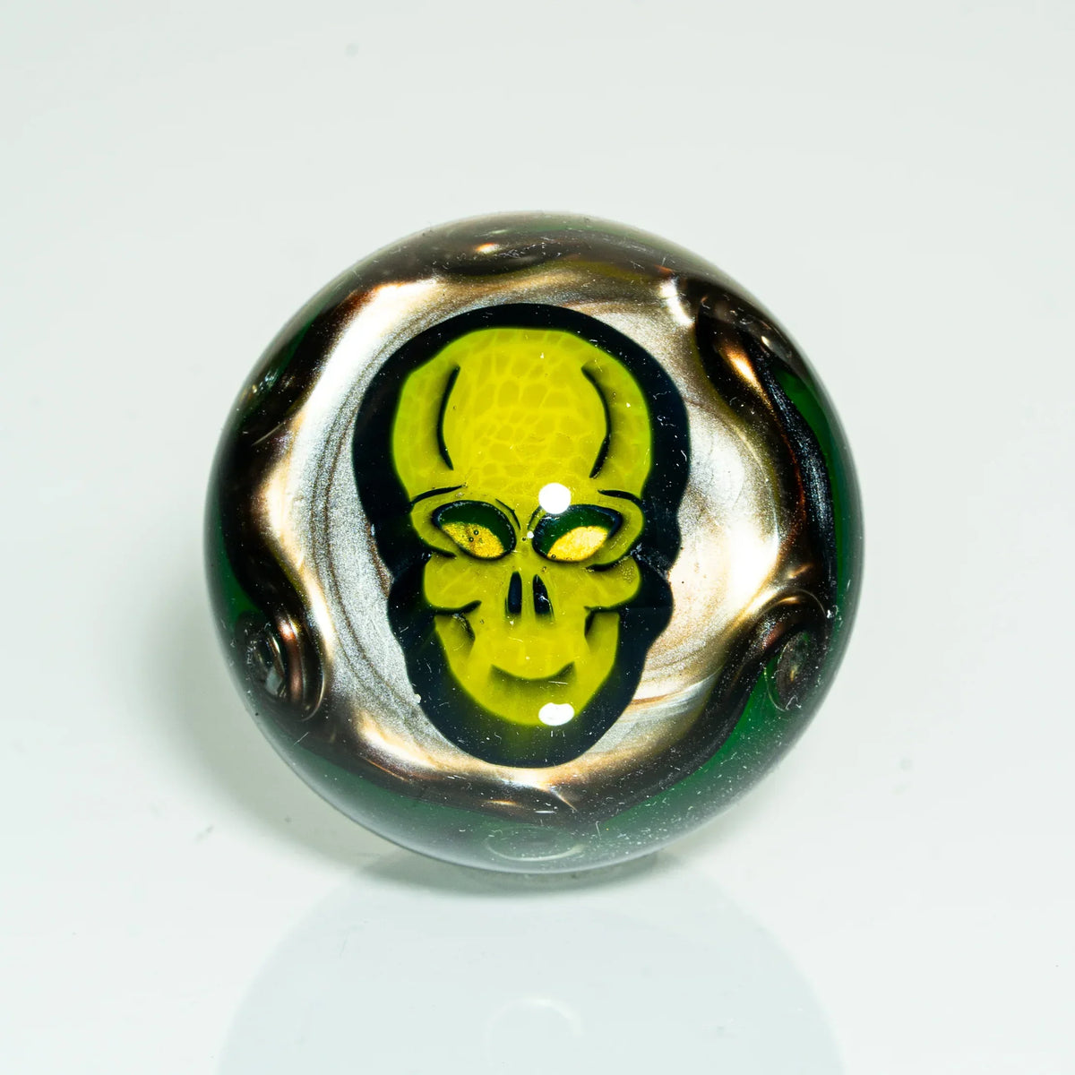 Hand-blown glass marble with yellow skull design and metallic rainbow swirls