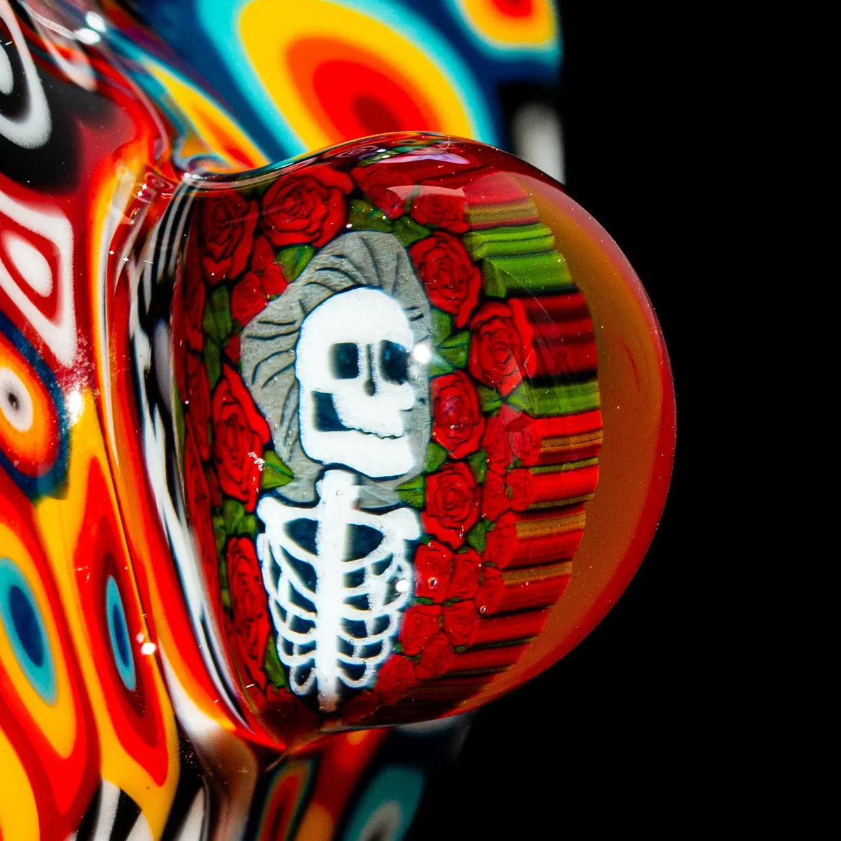 Close-up of colorful glass pipe featuring skeleton and roses design with vibrant patterns