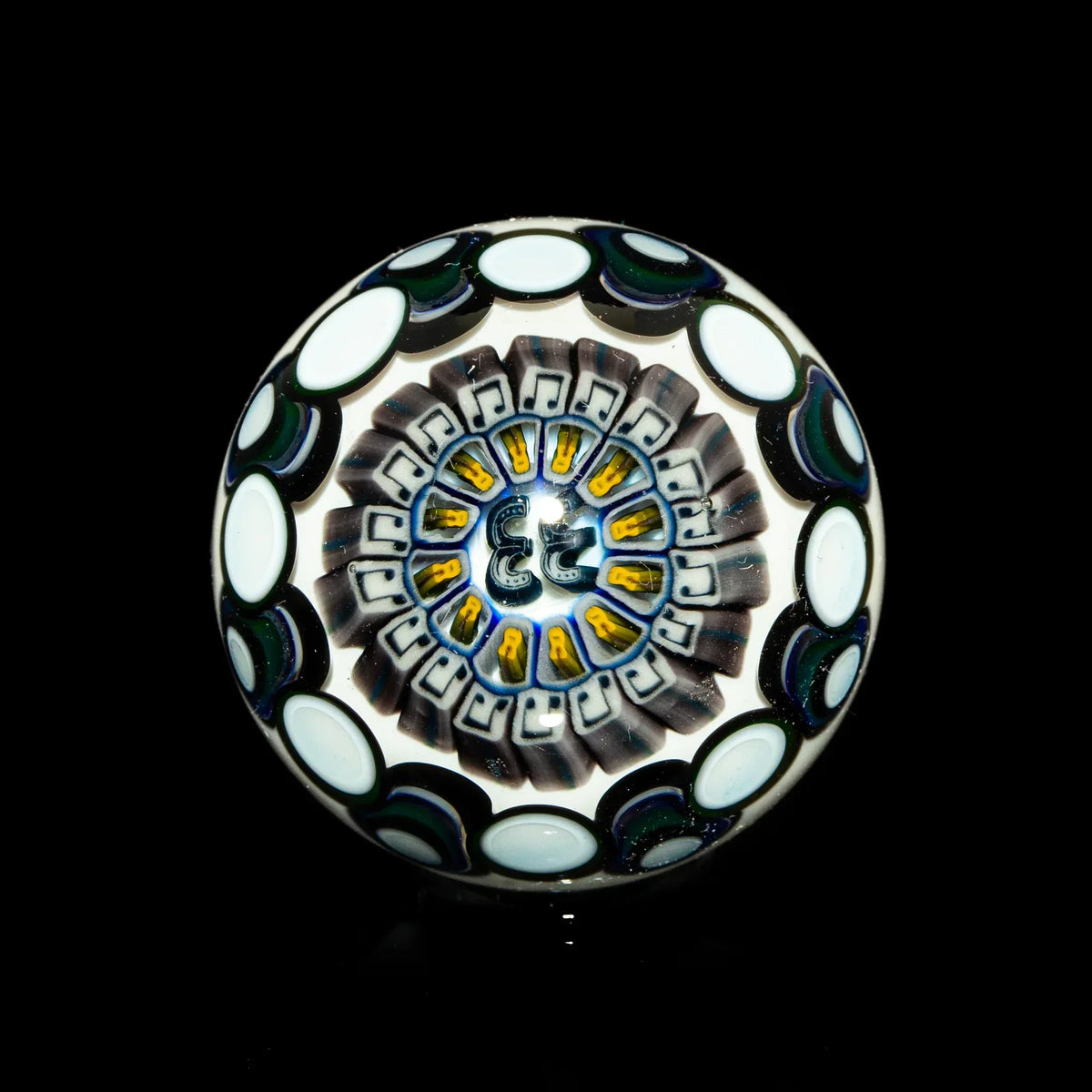 Hand-blown glass marble with intricate black, white, and opal geometric patterns