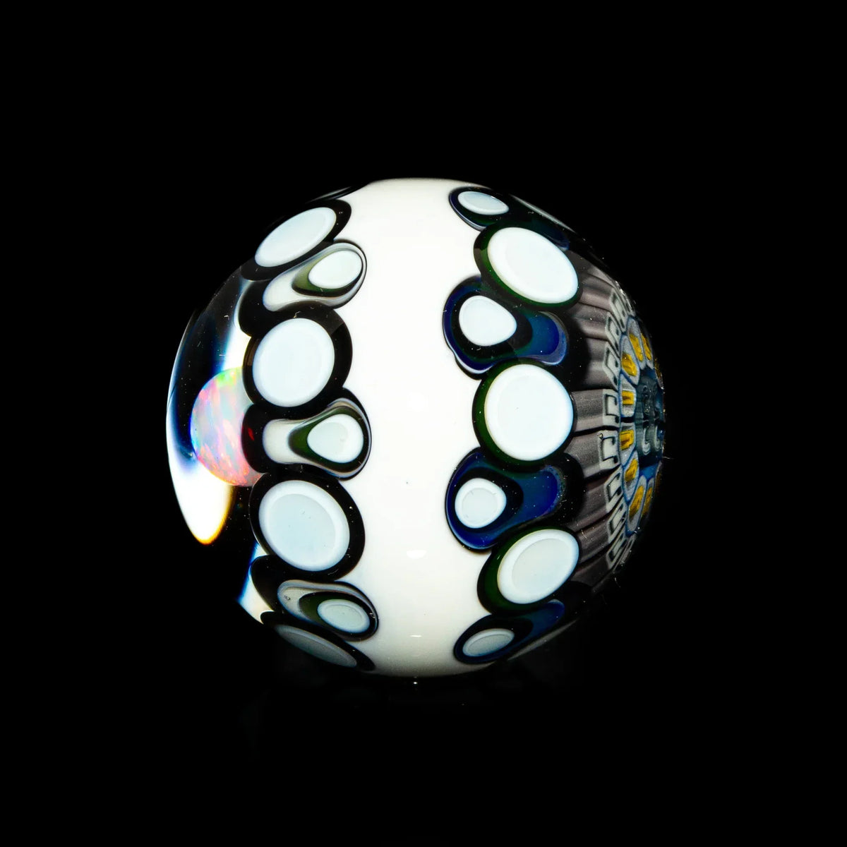 Black and white opal glass marble with circular patterns and colorful accents on black background