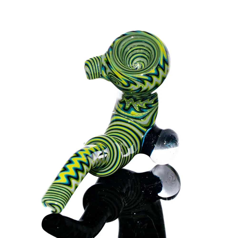 Green and yellow Sherlock glass pipe with black linework and marble accents on reflective surface