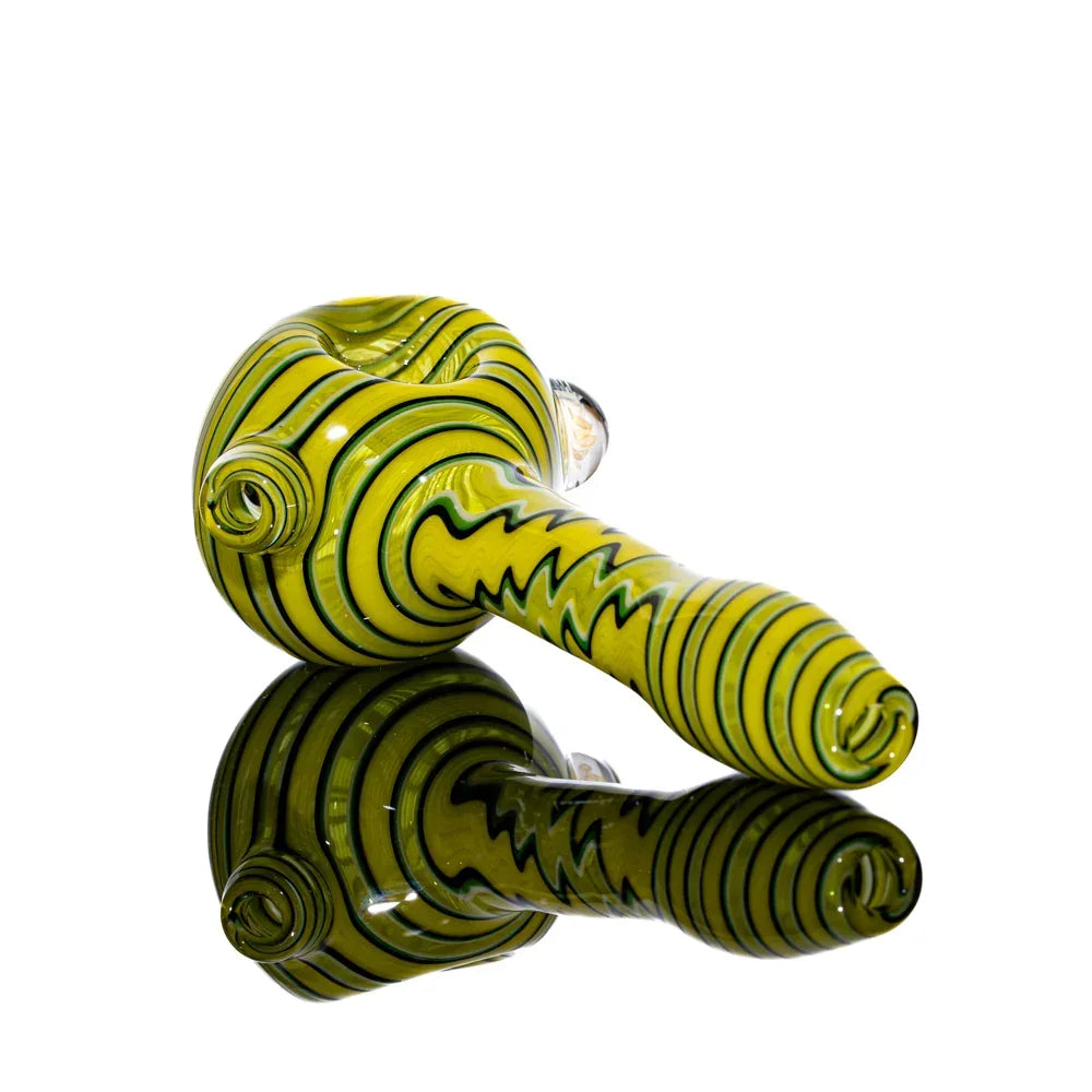 Yellow glass hand pipe with black and white linework, artistic smoking accessory reflected on surface