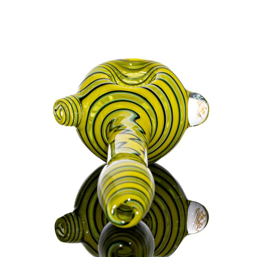 Yellow glass spoon pipe with white and black linework, displayed on reflective surface