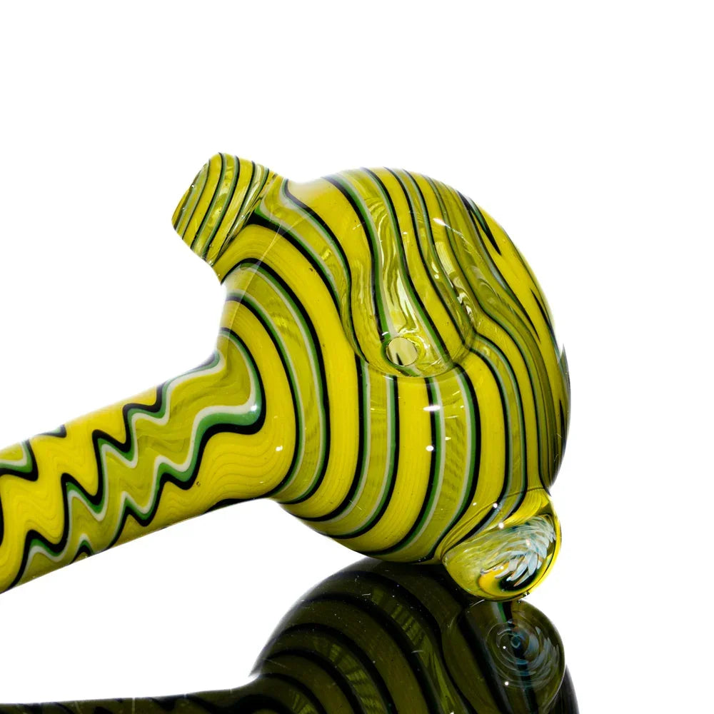 Yellow glass hand pipe with black and white linework on a reflective surface