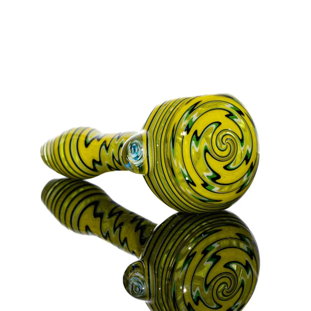 Yellow glass hand pipe with black and white swirled linework, reflected on white background