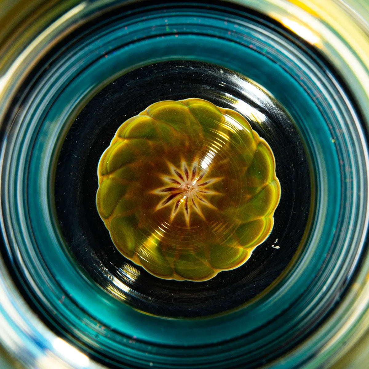 Close-up of amber and purple handblown glass pint with intricate dot stack pattern.