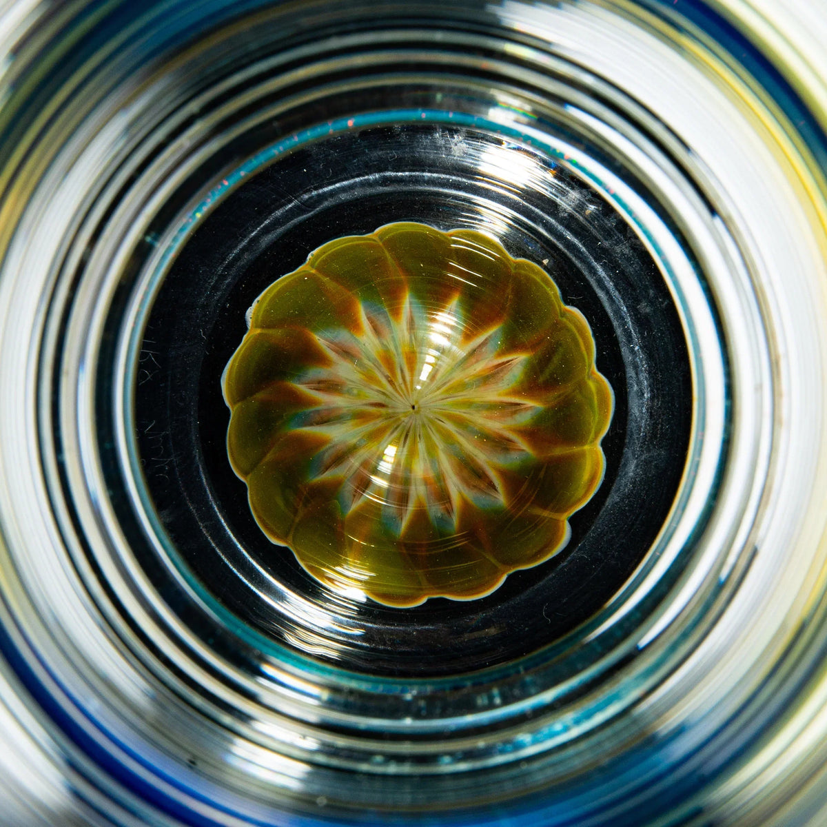 Colorful handcrafted glass pint glass with intricate dotstack pattern at base, top view