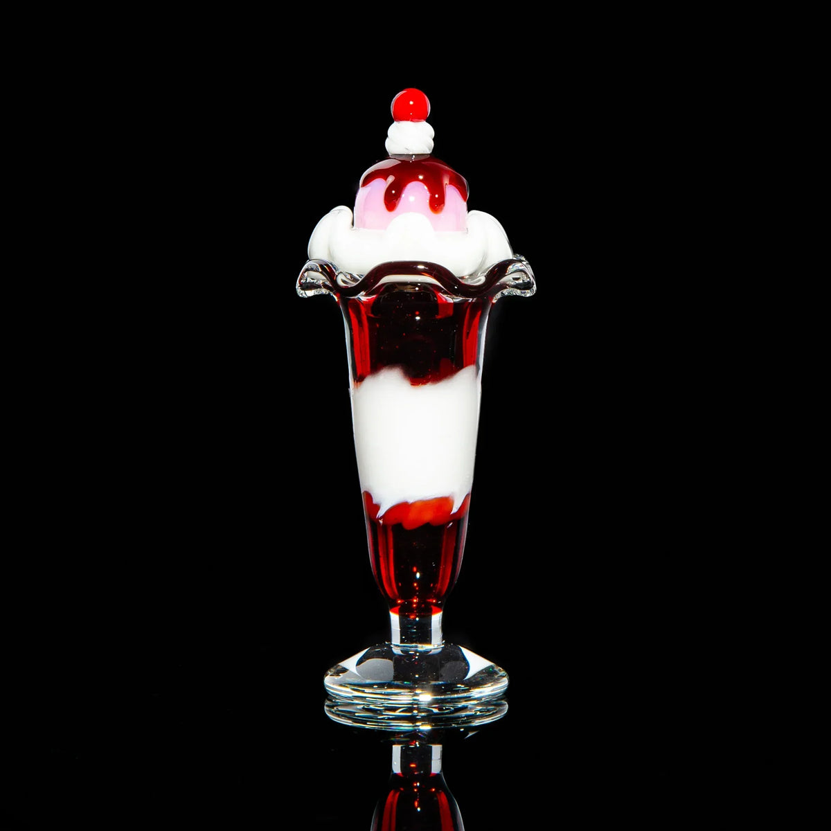 Glass sundae carb cap with red and white swirl, shaped like ice cream on black background.