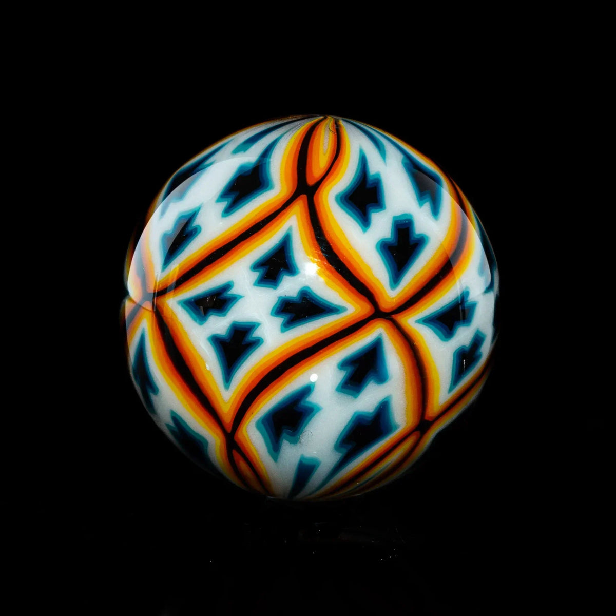 Handcrafted glass marble with geometric blue, orange, and white pattern on black background