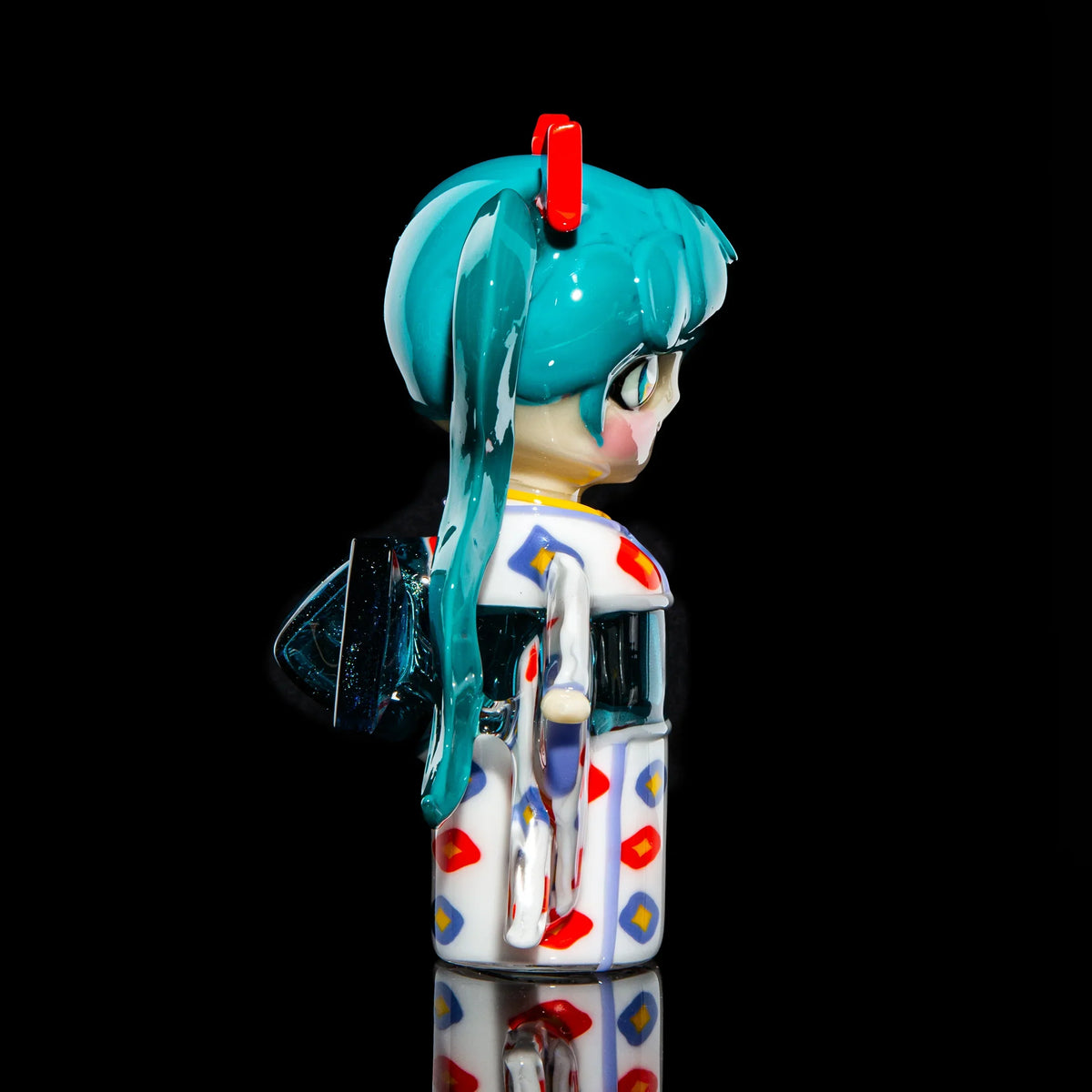 Hand-blown glass art piece shaped like an anime character with teal hair and colorful suit