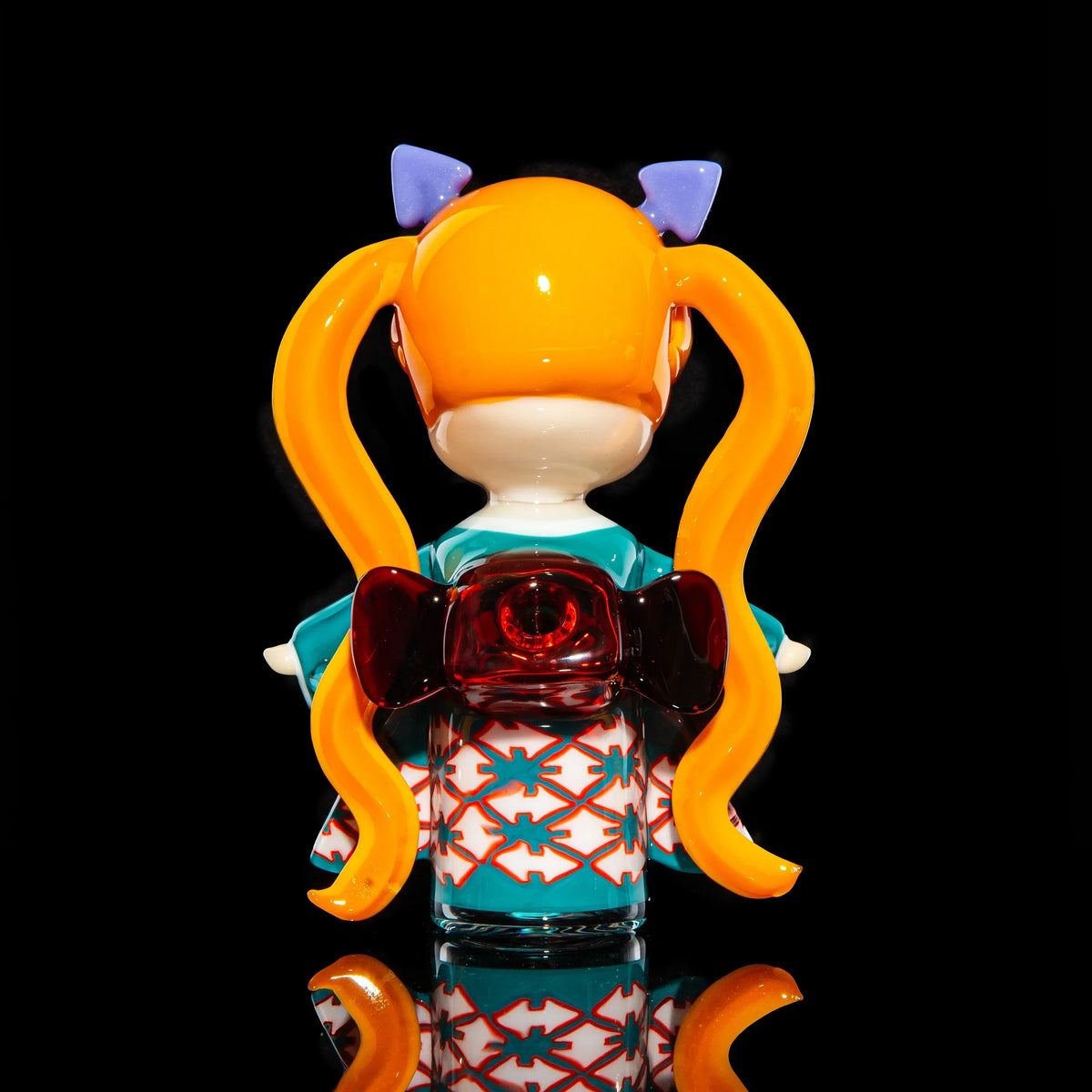 Hand-blown glass art piece of a cartoon girl with long orange pigtails in a kimono.