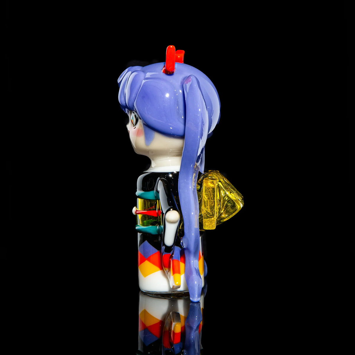 Hand-blown glass art figure with purple hair, geometric body, and yellow backpack on black background