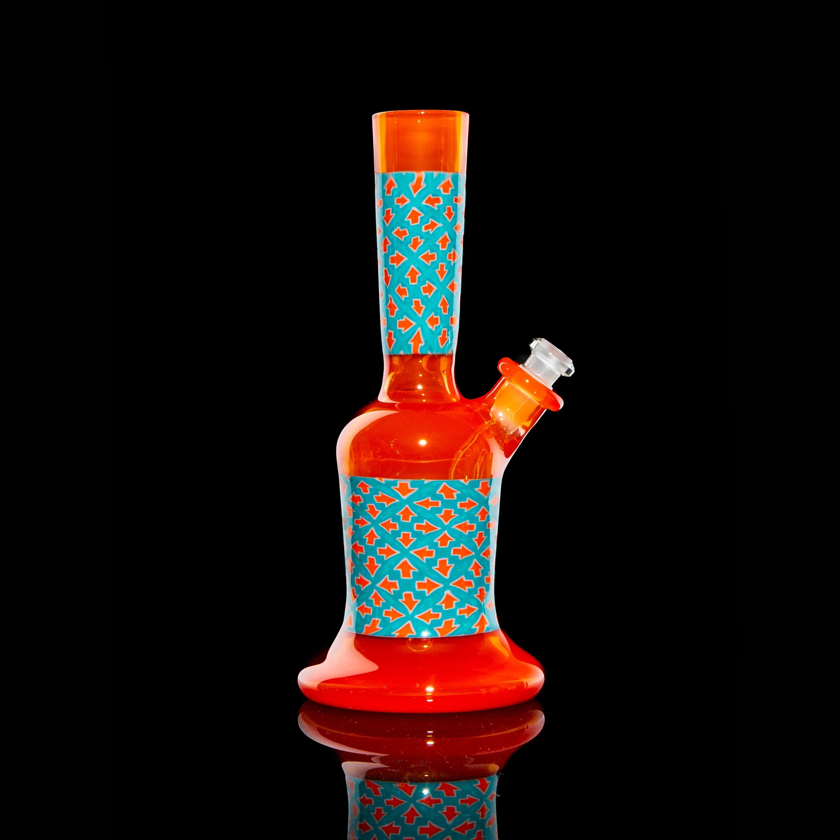Red and orange glass water pipe with blue geometric pattern on black background.