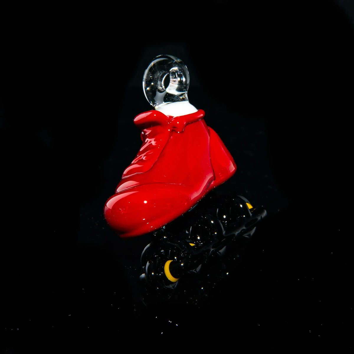 Red glass rollerblade pipe with black wheels on black background