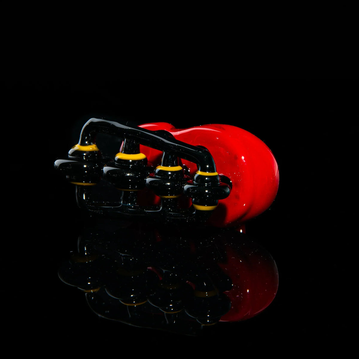 Red glass rollerblade-inspired pipe with black and yellow accents on glossy black background
