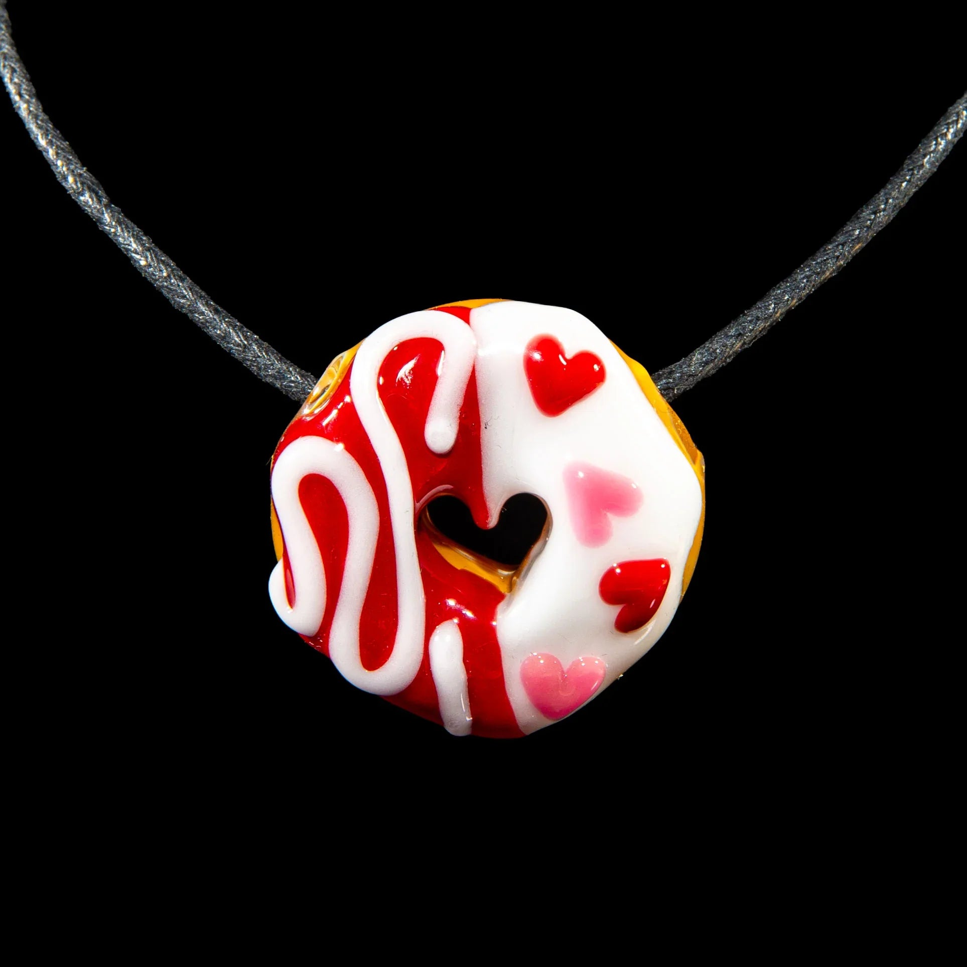 Glass donut pendant necklace with cherry and vanilla colors, heart sprinkles, black background