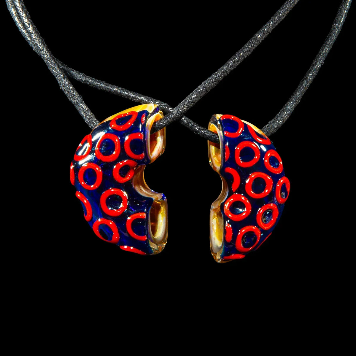 Colorful glass donut pendant necklace split in two with red circle designs on black cord