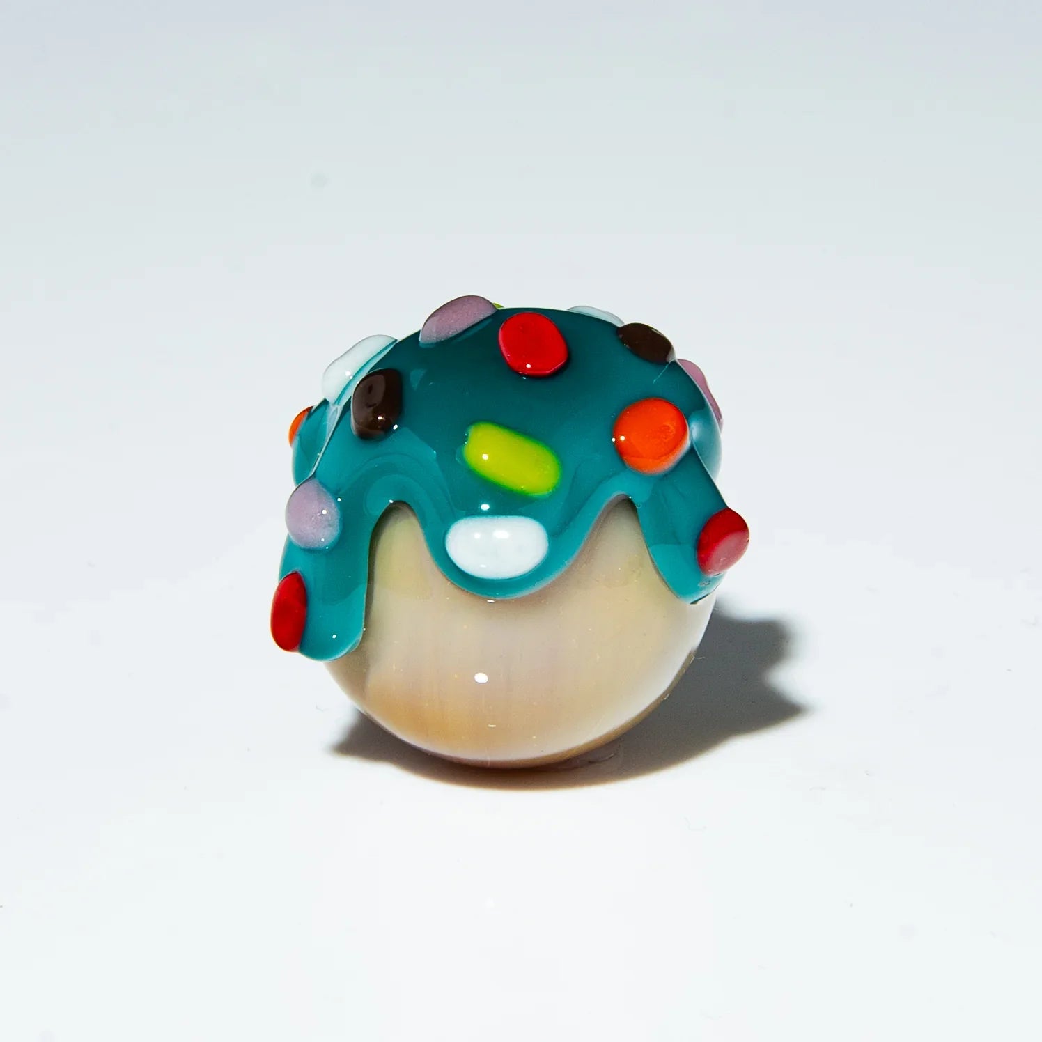 Colorful glass marble with blue top and rainbow sprinkles on white background