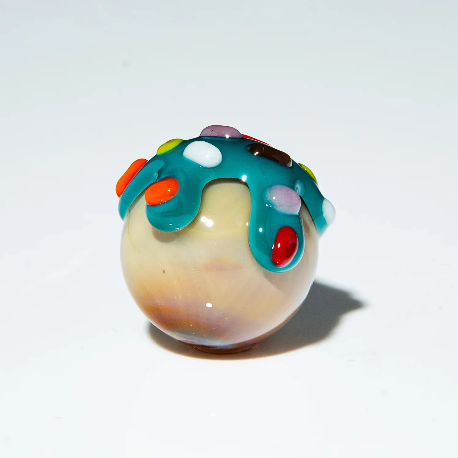 Handcrafted glass marble with blue drip design and colorful sprinkles accents