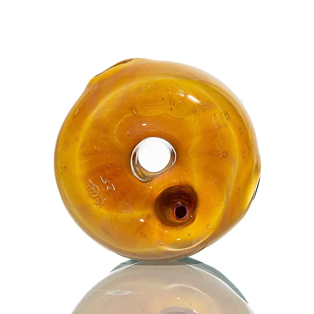 Amber glass donut-shaped dry pipe with smooth finish and central hole, on white background.