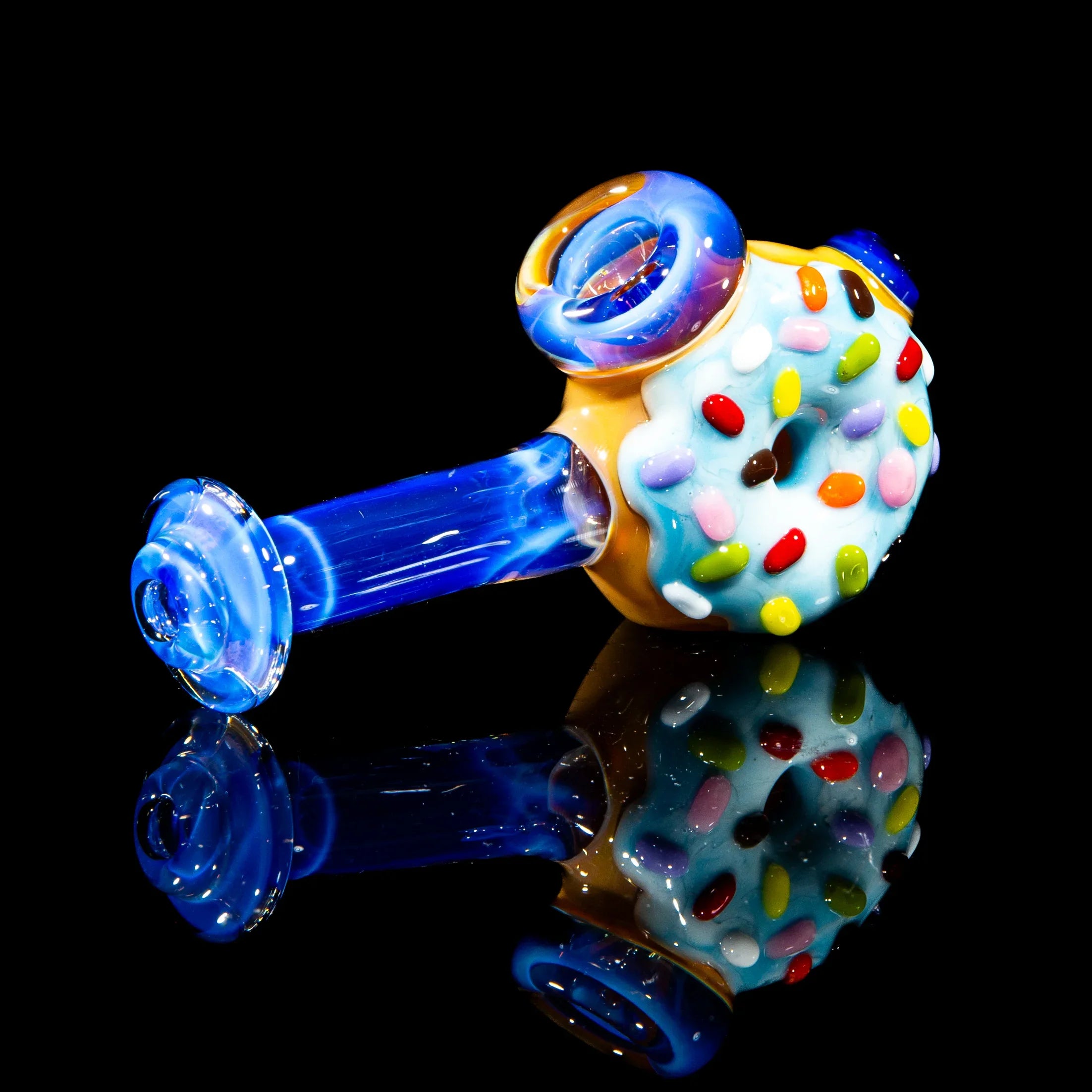 Blue glass hammer pipe with donut design and colorful rainbow sprinkles on black background