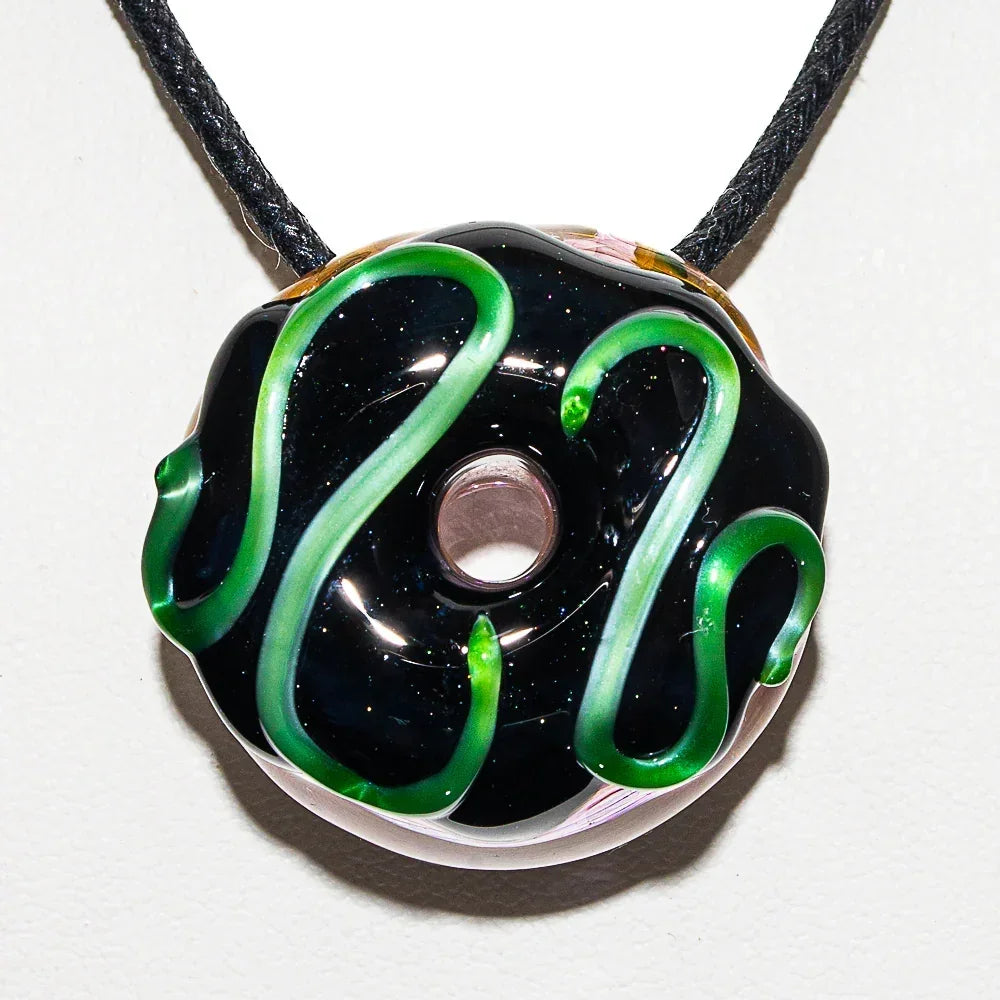 Glass donut pendant with black and green swirl design on a black cord