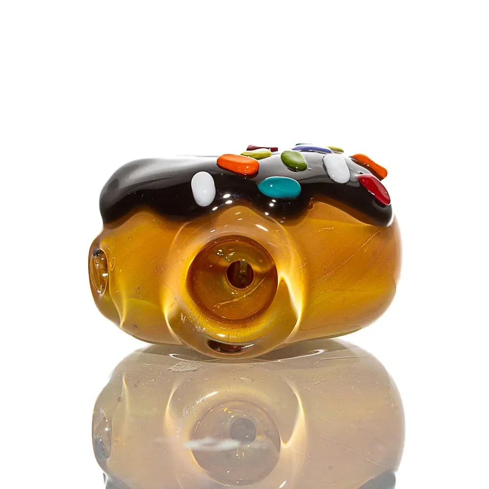 Glass hand pipe shaped like a mini donut with chocolate frosting and colorful sprinkles