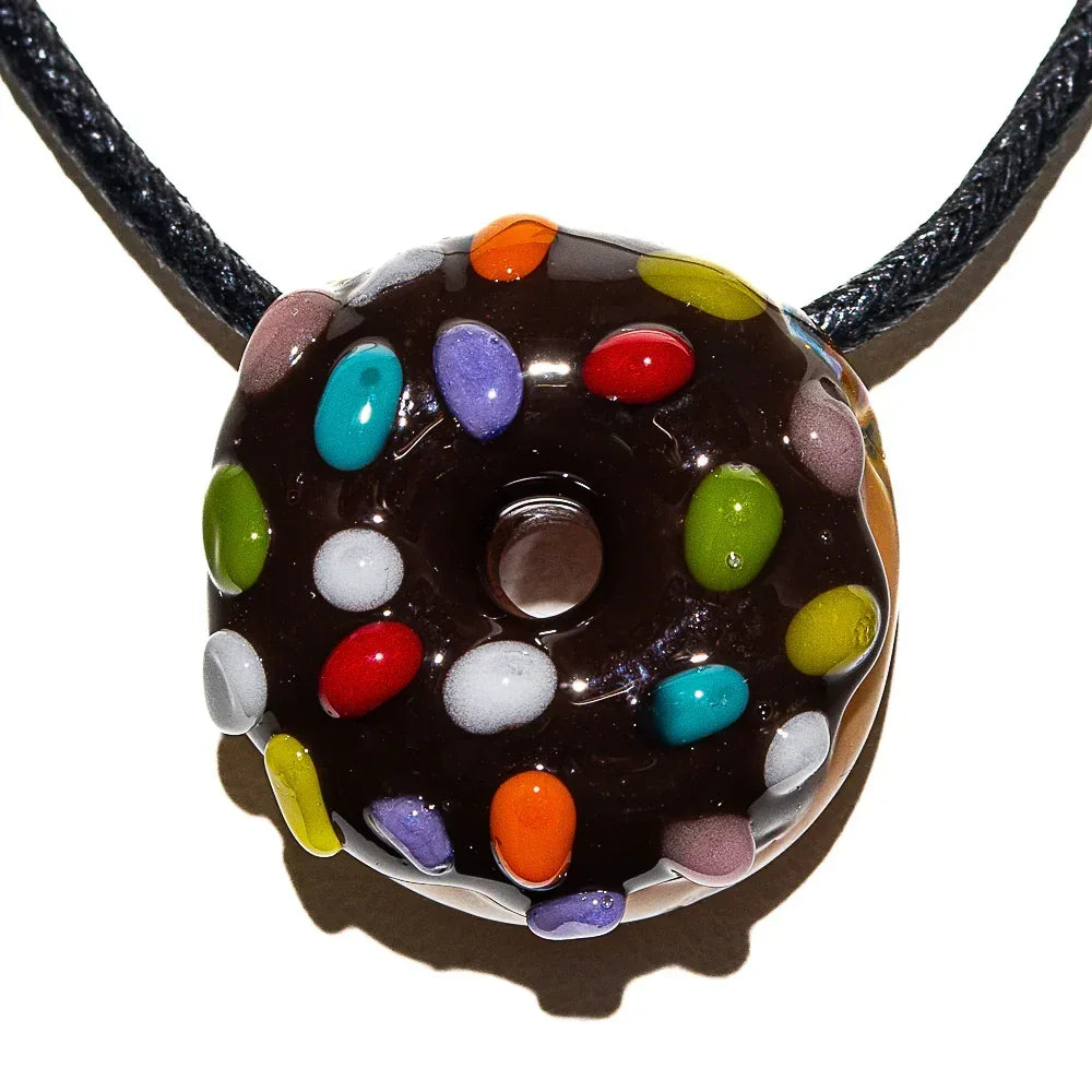 Chocolate frosted glass donut pendant with colorful sprinkles on a black cord necklace.