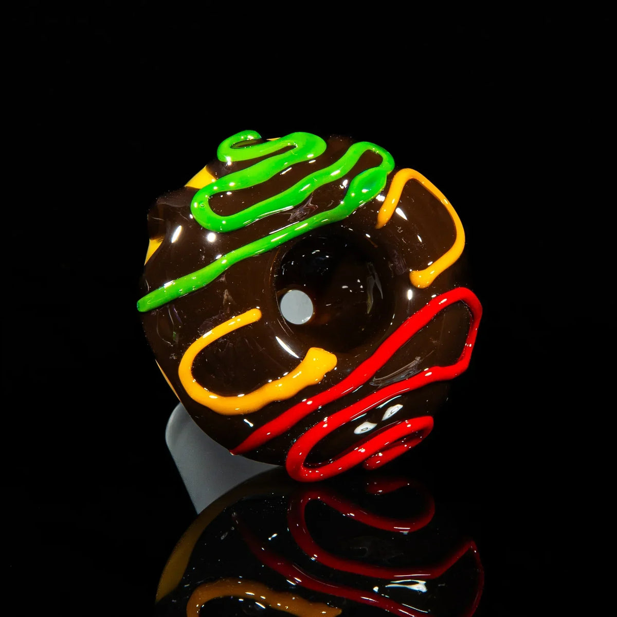 Chocolate glass slide with green, yellow, and red drizzle design on black background