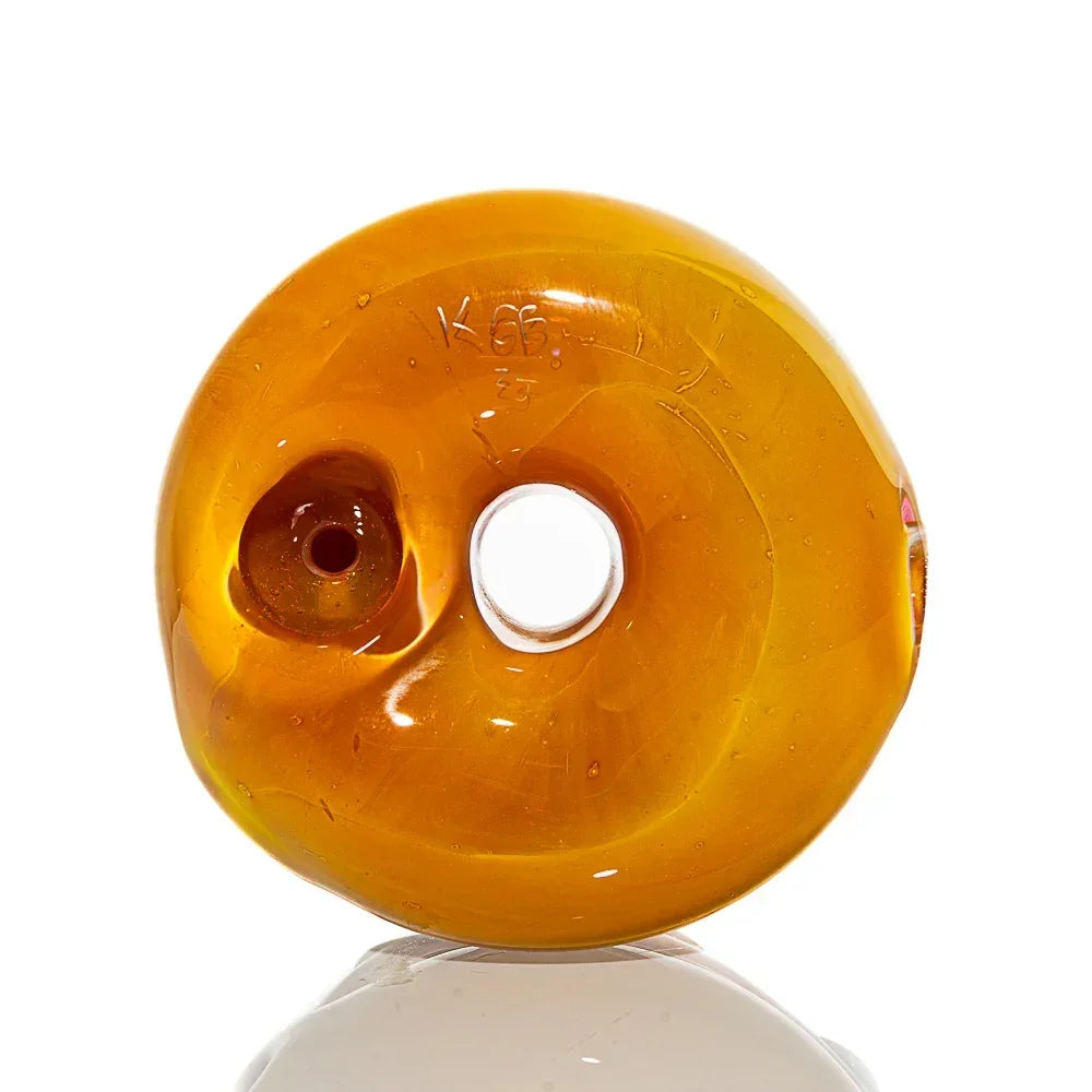 Amber glass donut dry pipe with central hole and rounded finish on white background