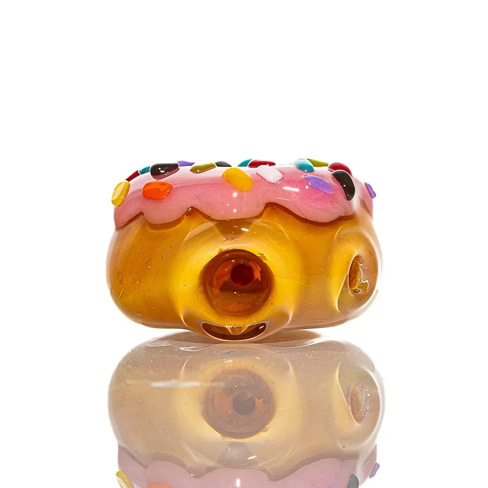 Strawberry frosted glass donut pipe with colorful sprinkle accents on white background.