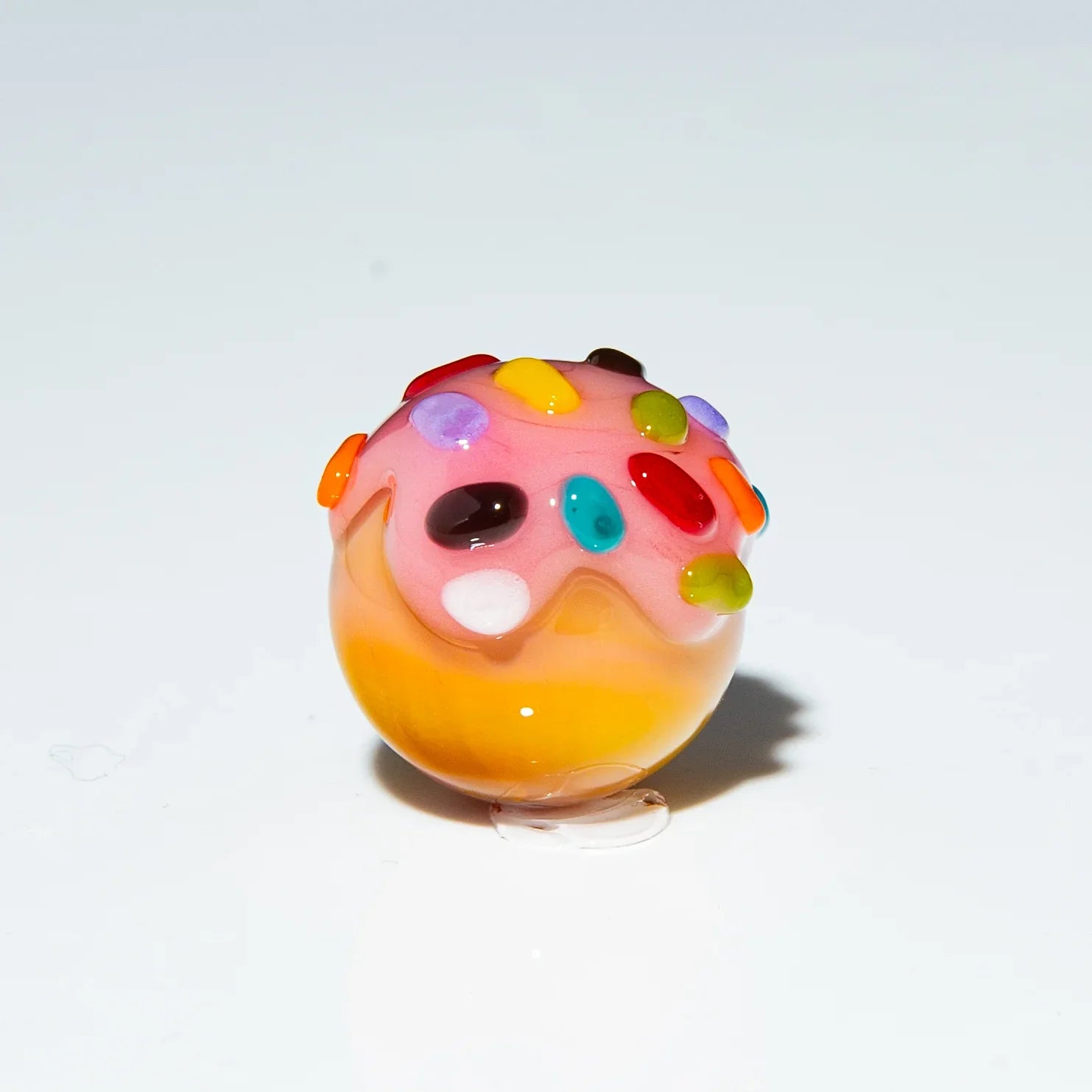 Colorful glass marble shaped like a strawberry dessert with rainbow sprinkles design