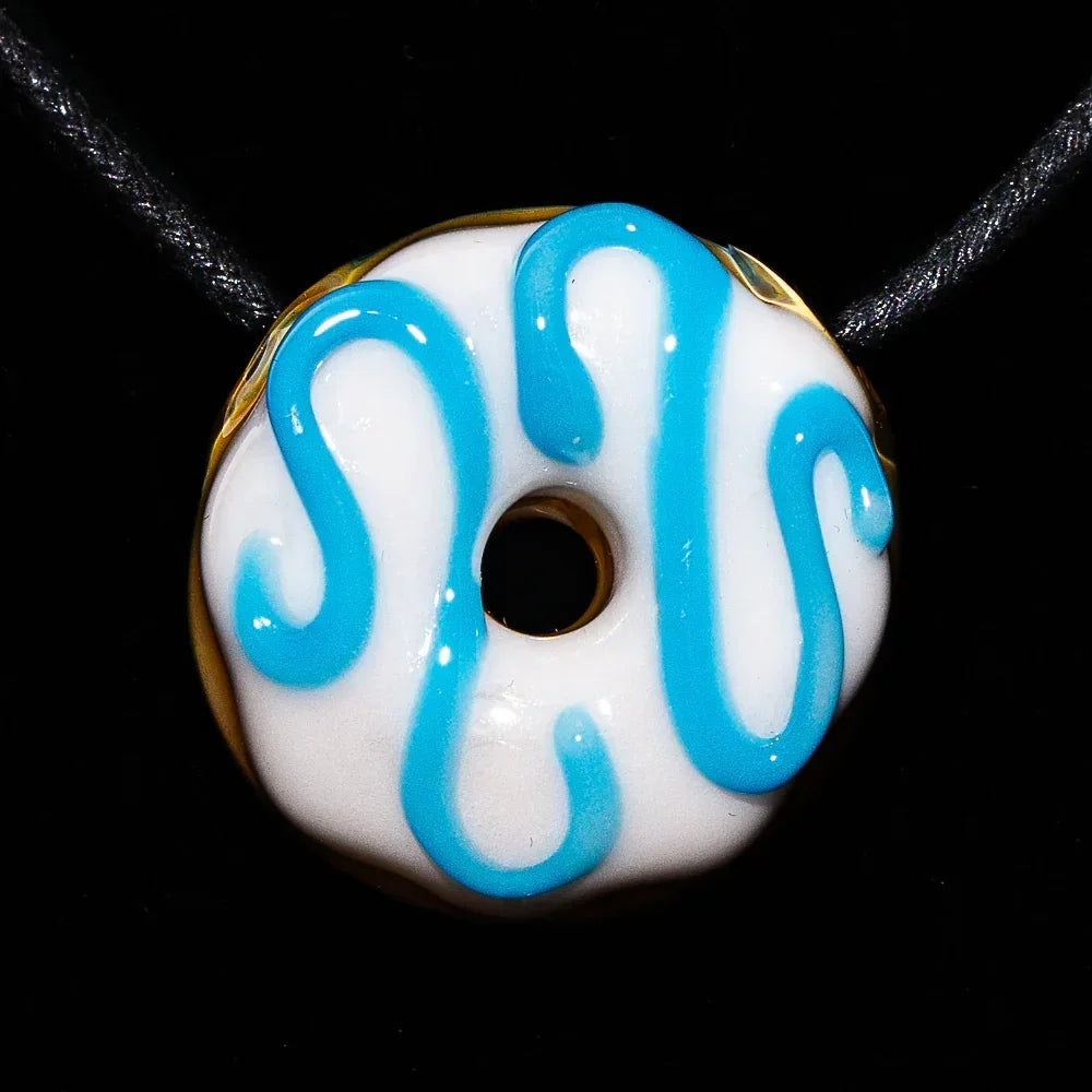 Glass donut pendant with white frosting and blue drizzle on a black cord necklace