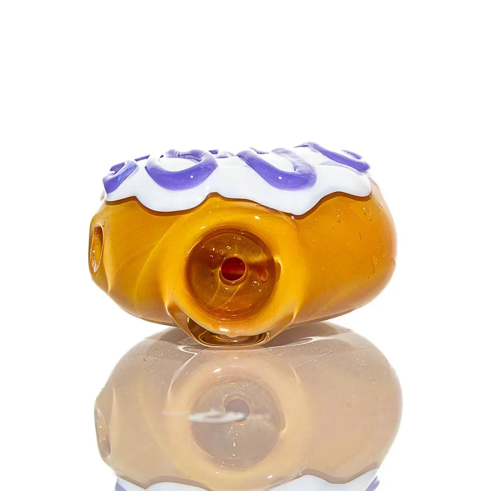 Vanilla frosted glass mini donut pipe with lavender drizzle accents on white background