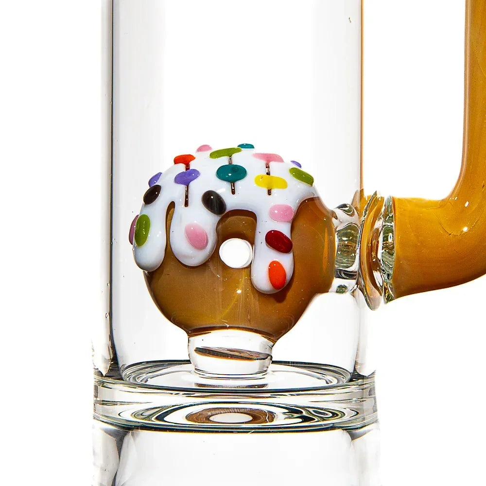 Close-up of a glass donut water pipe with frosted white icing and colorful sprinkles.