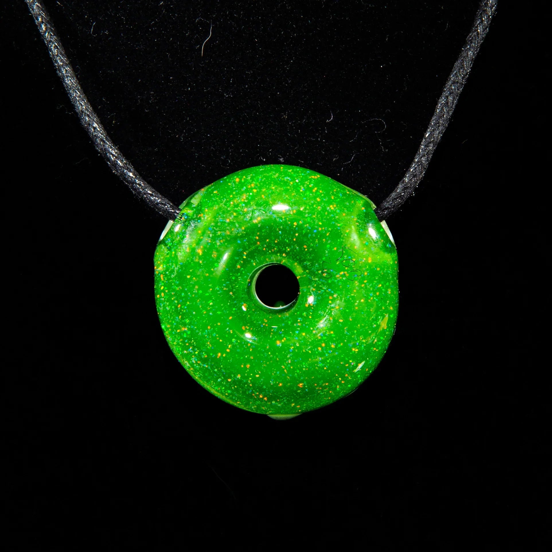 Green jade crushed opal glass donut pendant necklace on black cord, black background