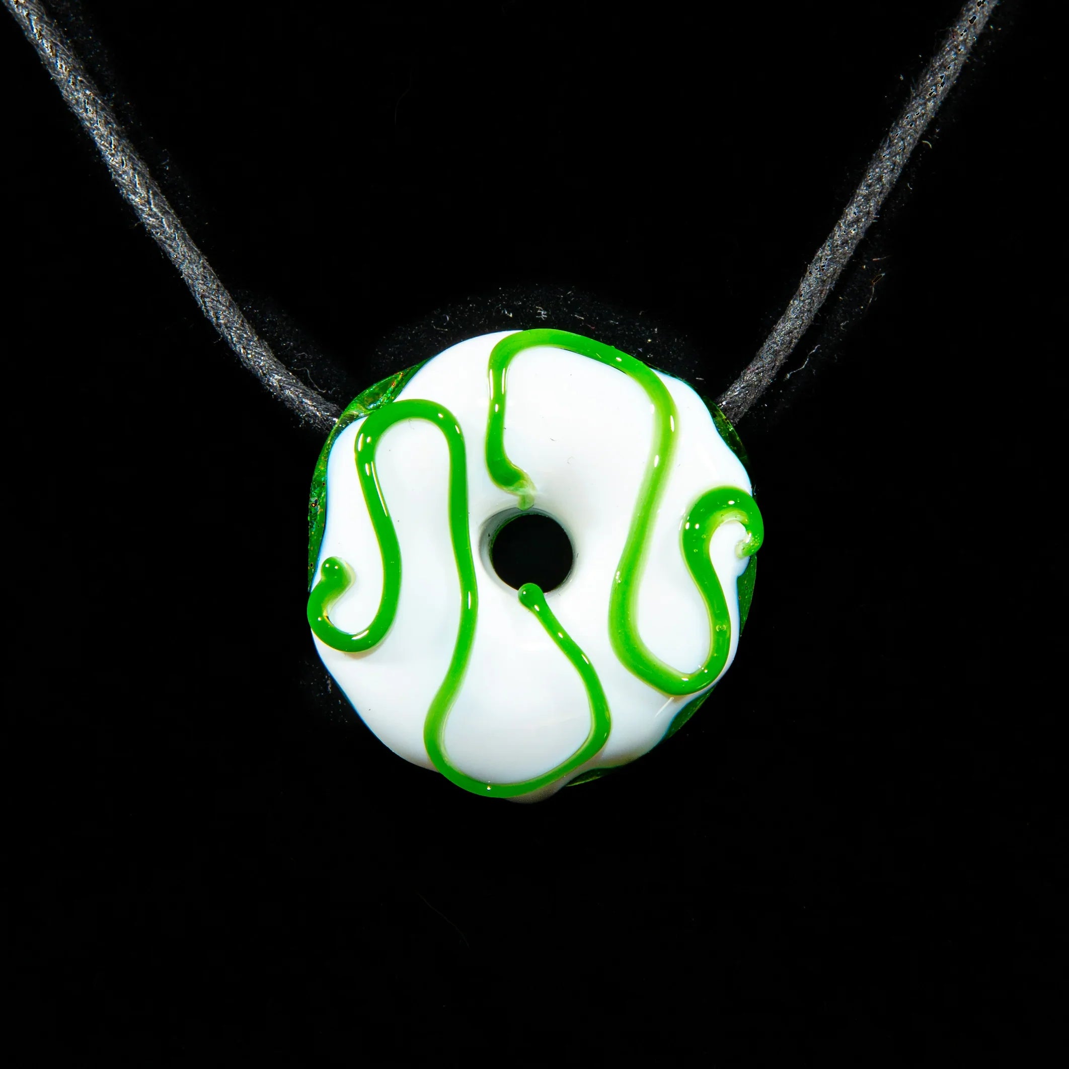 Handcrafted white glass donut pendant with green swirl on a black cord necklace