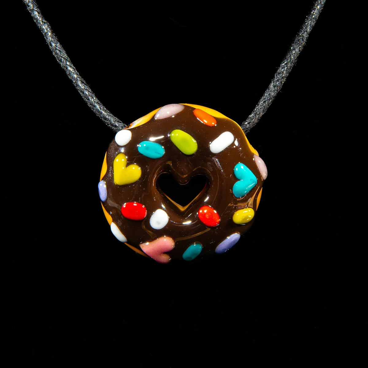 Glass donut pendant with chocolate glaze, rainbow heart sprinkles, and heart-shaped hole.