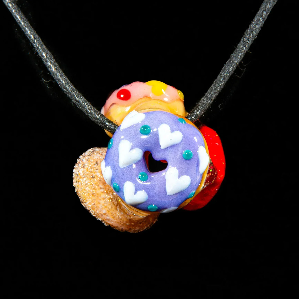 Glass donut cluster pendant with colorful heart accents on a black cord