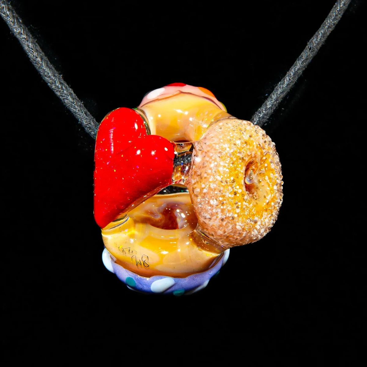 Glass heart and donut pendant with crushed opal accents on a black cord necklace