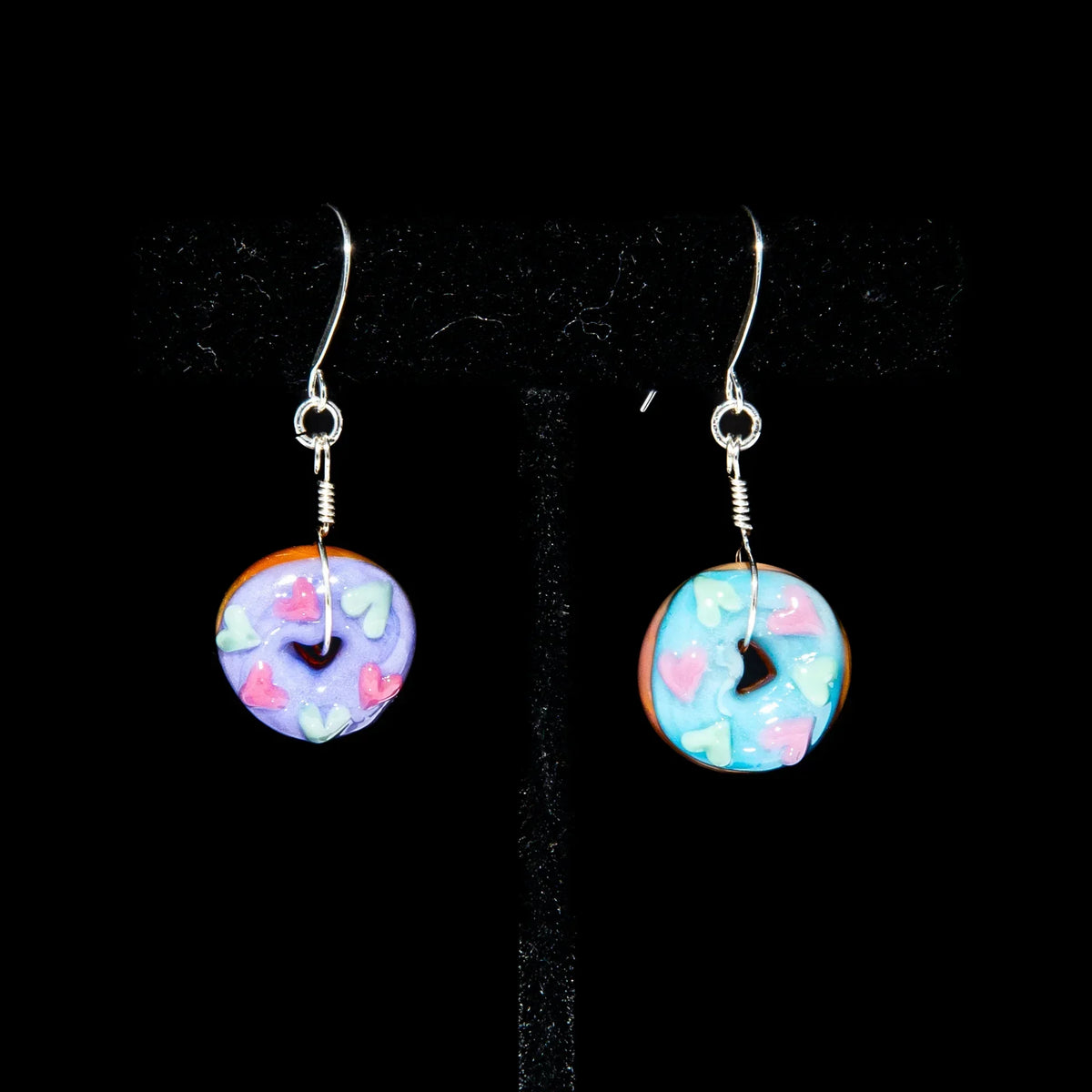 Mismatched donut earrings with lavender and blue icing and heart-shaped sprinkles