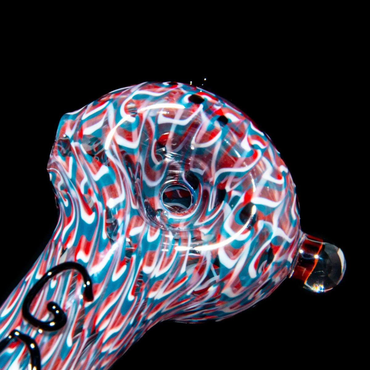Close-up of colorful red, white, and blue heady glass spoon pipe on black background