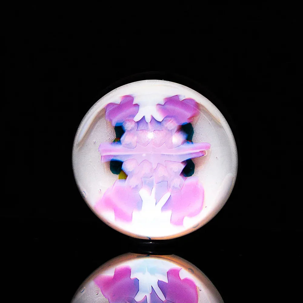 Handcrafted glass marble with pink and purple double milli pattern on black background