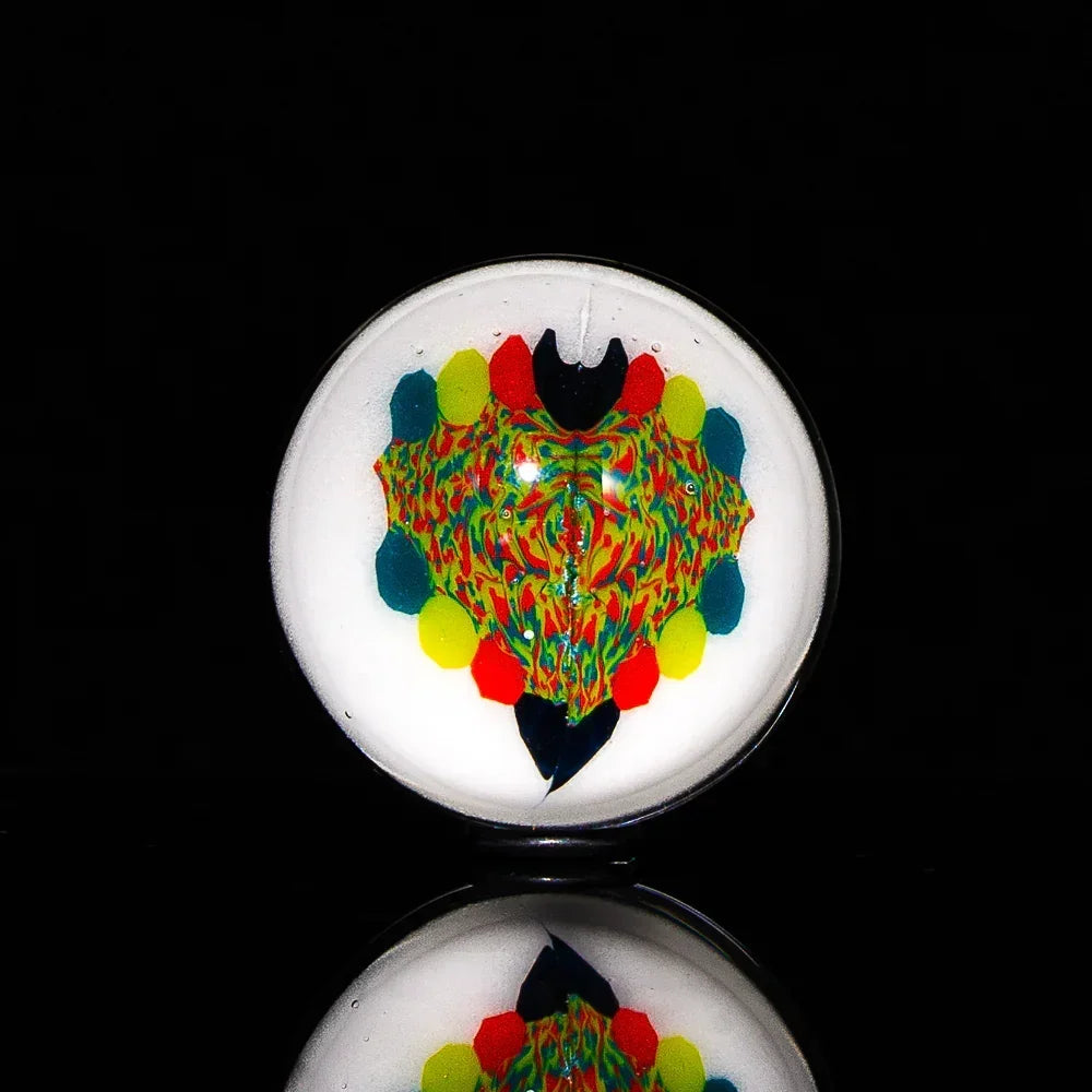 Colorful glass marble with abstract design on white background, reflected on black surface.