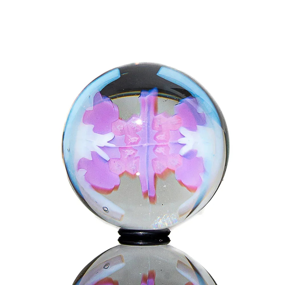 Colorful glass marble with abstract purple and blue design on a reflective surface