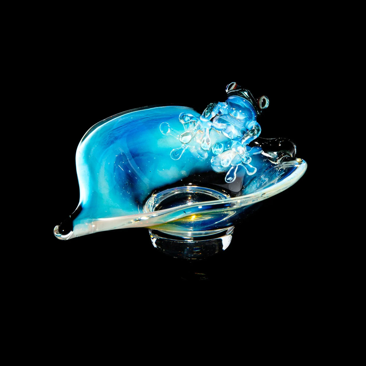 Handcrafted blue glass trinket dish shaped like a frog on a leaf against black background