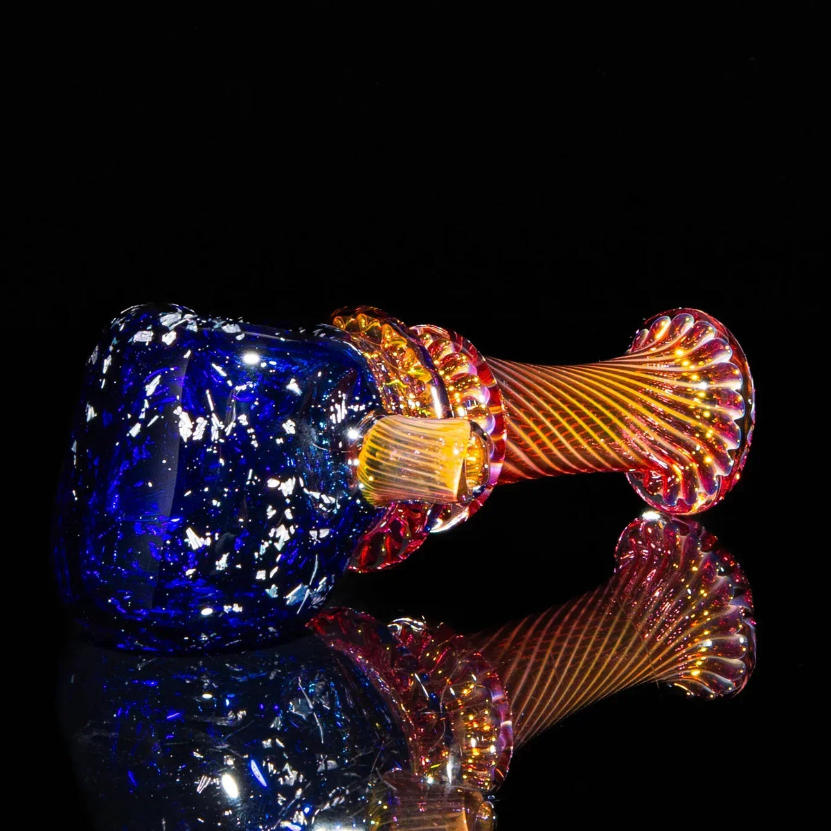 Colorful hand-blown glass spoon pipe with blue and fumed swirled design on black background