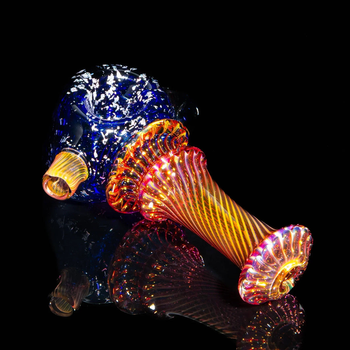 Colorful glass spoon pipe with blue, orange, and gold fume swirl design on black background.
