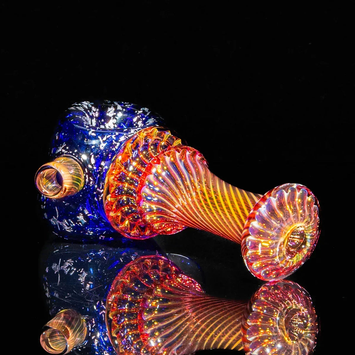 Colorful glass spoon pipe with blue bowl, swirling orange and yellow fume design on black background