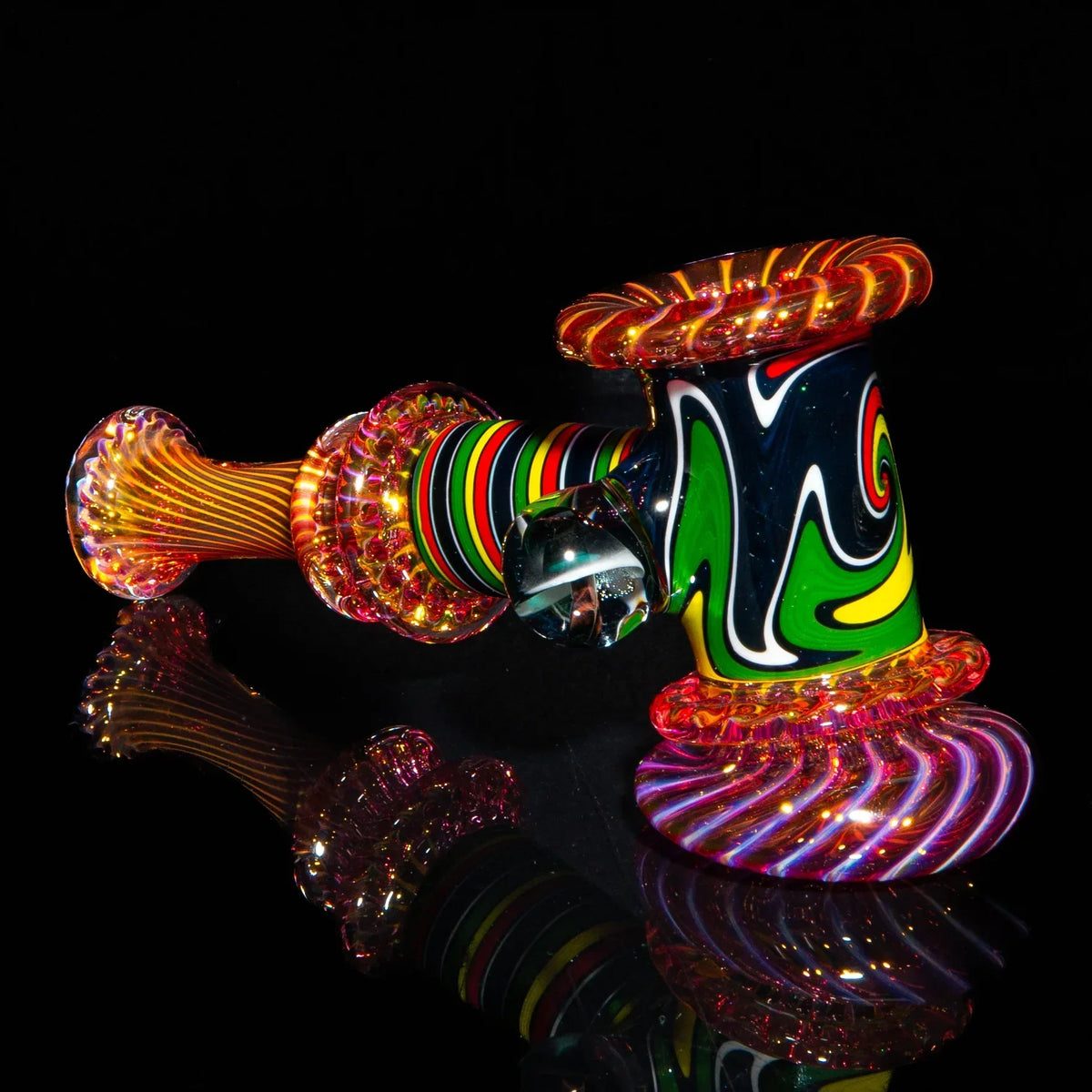 Colorful glass hammer pipe with vibrant rasta linework and fumed accents on black background